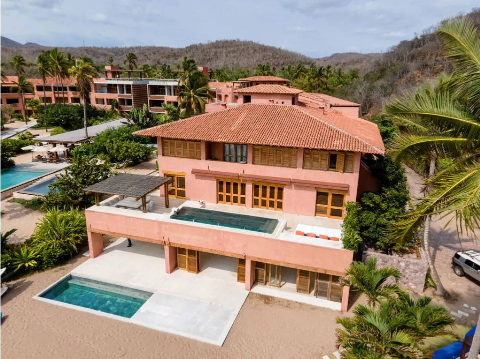 An aerial view of a tropical beach with palm trees and a swimming pool.